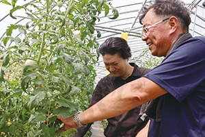 トマト栽培のコツを教える鈴木さん（右）