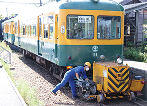 「白山前」の表示を出しているかぼちゃ電車と鉄道車両用車両移動機「アント」の写真