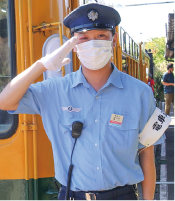 かぼちゃ電車保存会、電車運転士・関川拓馬（たくま）さんが当時の新潟交通電車線の制服・帽子を被り、かぼちゃ電車の脇で敬礼をしてる写真